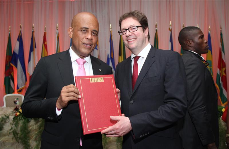 HE Michel Joseph Martelly, President of the Republic of Haiti receives a special leather-bound edition of the official Summit publication from Alastair Harris, Executive Publisher and Editor of FIRST 
